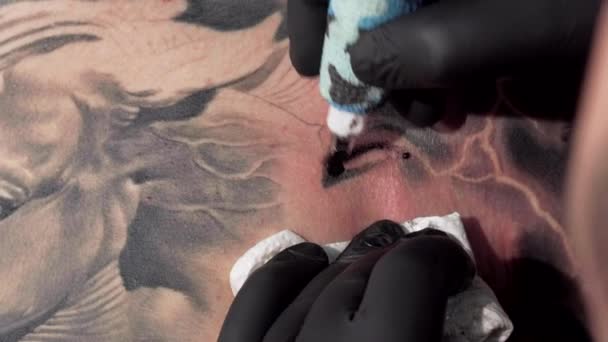 Corte macro disparo de un tatuador utilizando la máquina de tatuaje, haciendo tatuajes. Corta la toma deslizante de un artista profesional del tatuaje dibujando en la piel de un cliente, usando el equipo del tatuaje
 - Metraje, vídeo