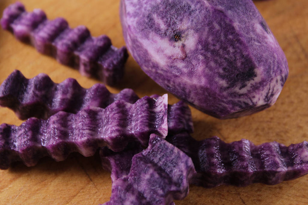 крупним планом зверху нарізані хвилясті скибочки фіолетової картоплі. Декоративний дизайн їжі
.  - Фото, зображення
