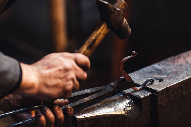 blacksmith makes an artistic forging of hot metal on the anvil. - Photo, Image