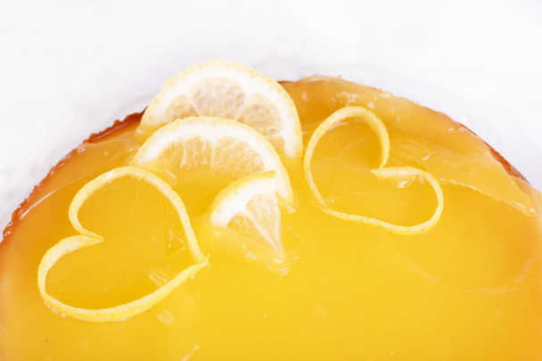 レモンの皮のクローズ アップで飾られた白地にレモン チーズケーキ - 写真・画像