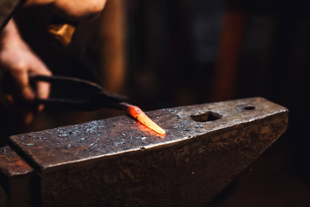 herrero hace una forja artística de metal caliente en el yunque
. - Foto, imagen