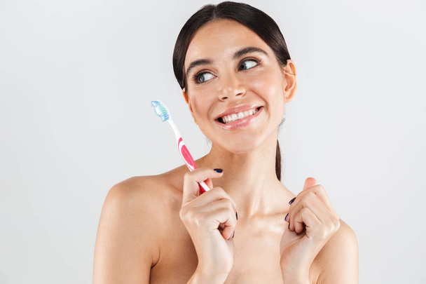 Beauty portrait of an attractive healthy woman standing isolated over white background, showing a toothbrush - Zdjęcie, obraz