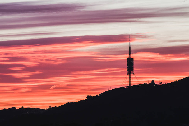 Esta es una torre de telecomunicaciones en Barcelona. Es la hora de la puesta del sol y el cielo tiene colores espectaculares como púrpura, naranja y rojo
. - Foto, Imagen