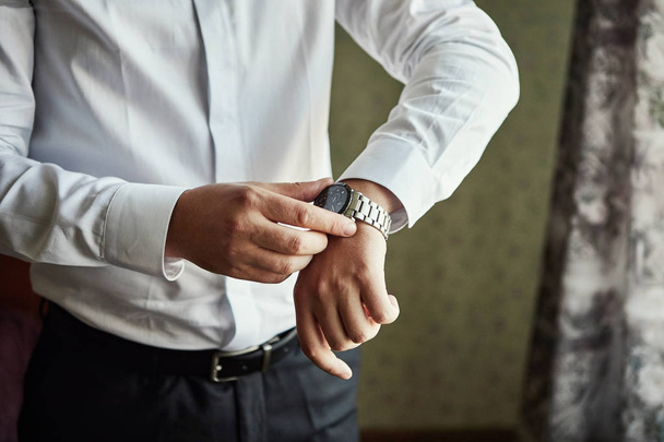 homem de negócios verificando o tempo em seu relógio de pulso, homem colocando relógio na mão, noivo se preparando pela manhã antes da cerimônia de casamento. Moda Masculina - Foto, Imagem