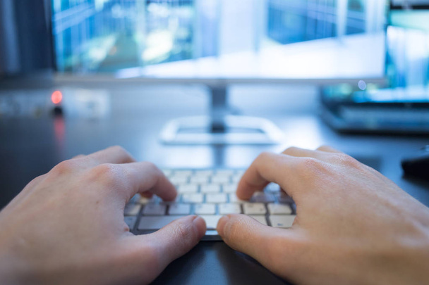 Hands are typing on a white keyboard, screen in the blurry background - Photo, image