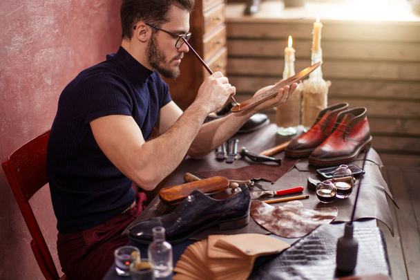 attractive bearded man painting the surface of the soles - Photo, Image
