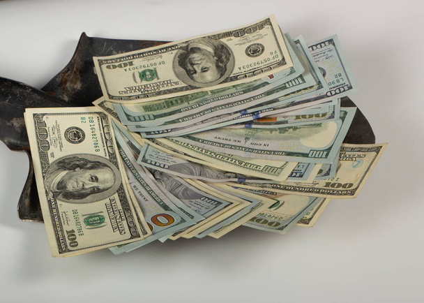 Argent, cent dollars, billets sur une vieille pelle de construction, sur fond blanc. Gros plan
 - Photo, image