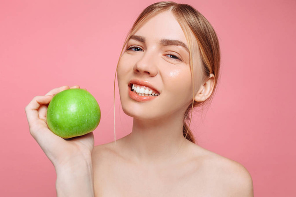 Portrait of a happy beautiful woman holding an apple, on a pink background. Natural beauty concept - Foto, immagini