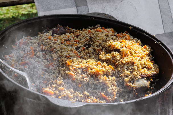 Oezbeekse pilaf wordt gekookt in een ketel op de beurs. - Foto, afbeelding