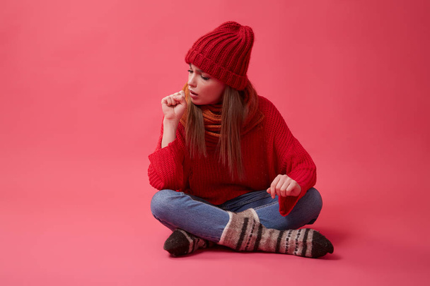 Girl suffering from a sore throat or flu coughs. Red background. - Foto, afbeelding
