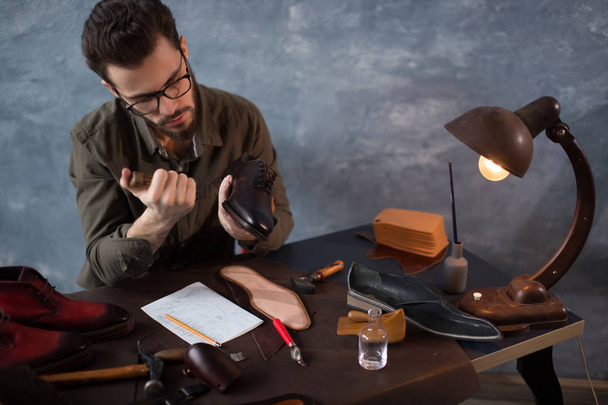 shoemaker in glasses repairing the broken sole of a boot - Photo, Image