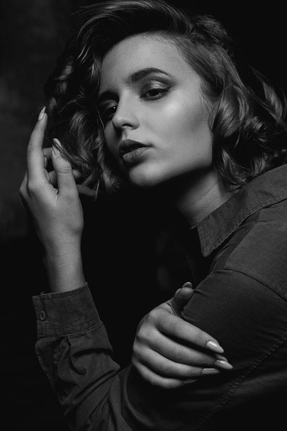 Portrait of tender brunette woman with curly hair and beautiful makeup posing with contrast light. Black and white toning - Photo, Image