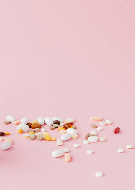 group of capsules and pills in different colors and shape isolated on pink background. - 写真・画像