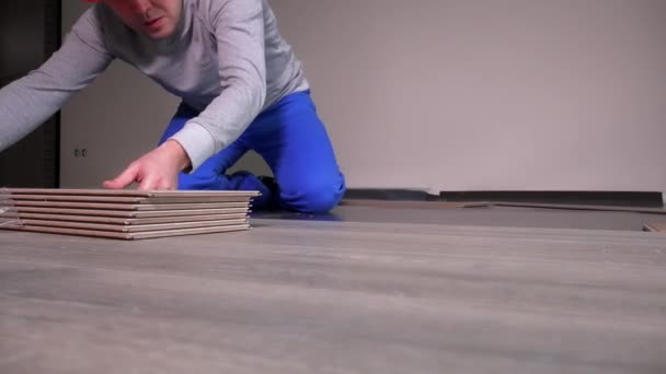 Trabajadores profesionales que ponen tableros laminados de roble de madera en el piso en una habitación nueva
 - Imágenes, Vídeo