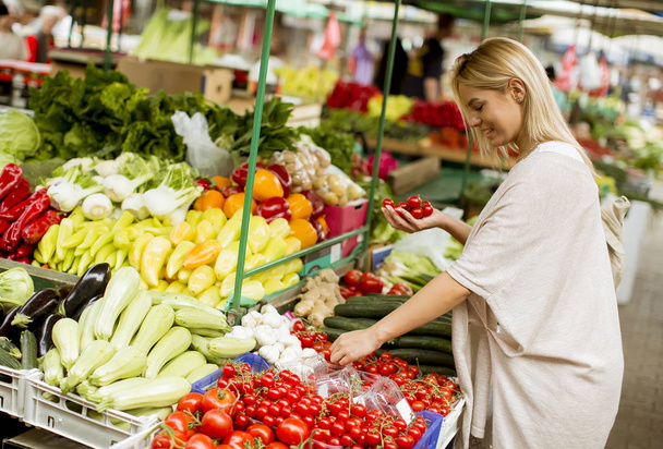 Näkymä kaunis nuori nainen ostaa vihanneksia markkinoilla
 - Valokuva, kuva