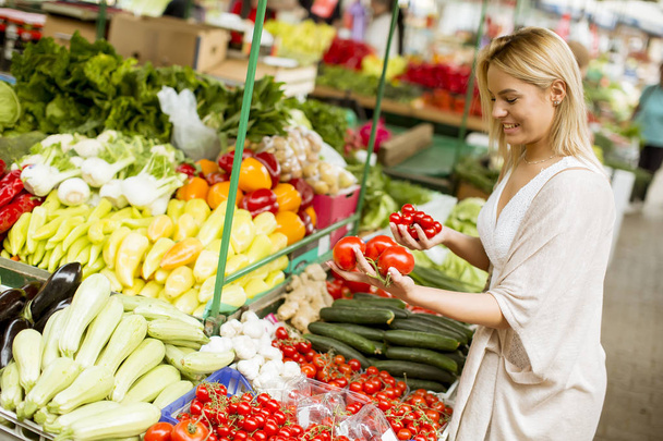 Vista a bella giovane donna che compra verdure al mercato
 - Foto, immagini