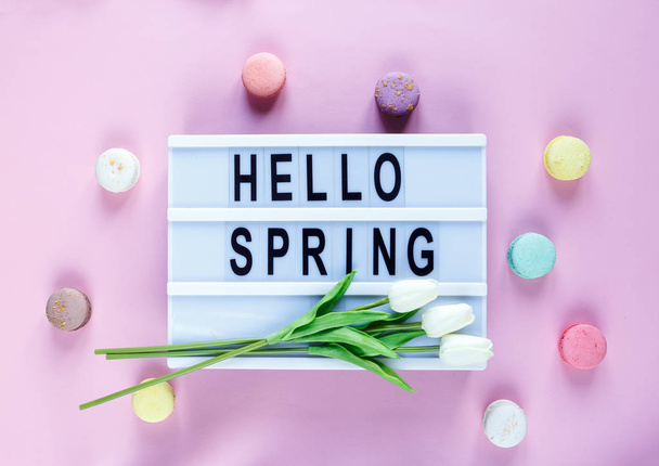 Lightbox con título Hola primavera y tiernos tulipanes, macarrones sobre fondo rosa. Decoración, fondo de primavera. Vista superior, plano
  - Foto, Imagen