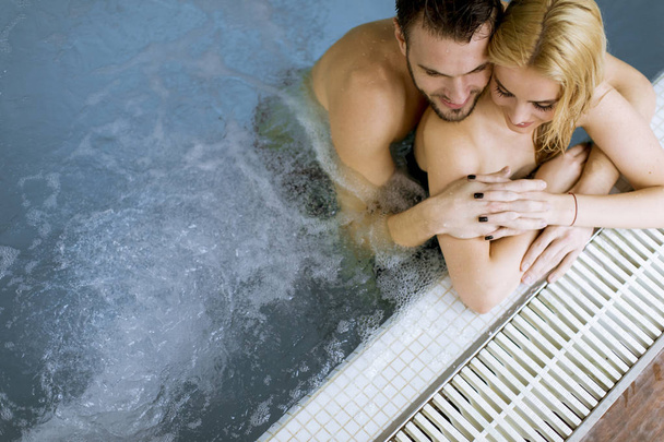 Loving young couple relaxing in the swimming pool at spa center - Photo, Image