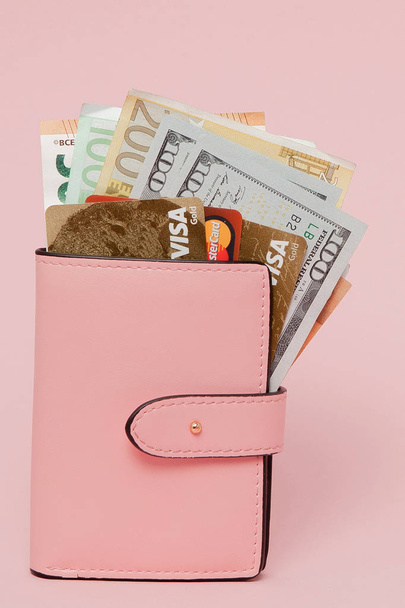 Bank branch. Choosing a credit card for salary. Bank cards, dollars and euro in a pink wallet on the pink background with copy space. - Fotoğraf, Görsel
