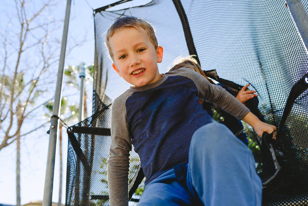 Niño divirtiéndose en primavera en un trampolín al atardecer
. - Foto, Imagen