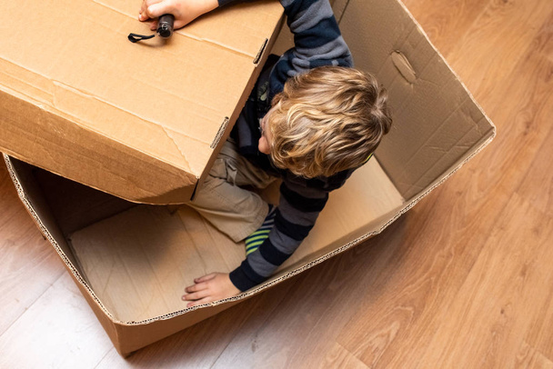 Niño jugando dentro de una caja de cartón
. - Foto, imagen