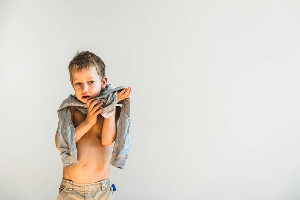 Child trying to take off his shirt and undress on his own. - Photo, Image
