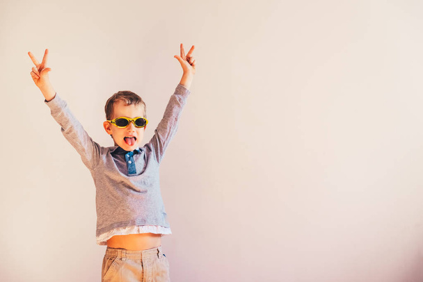 Bambino con divertenti occhiali da sole che sollevano le braccia eccitato nel segno della vittoria
. - Foto, immagini