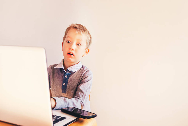 Ребенок с очень выразительным лицом перед ноутбуком с сердитым жестом
. - Фото, изображение