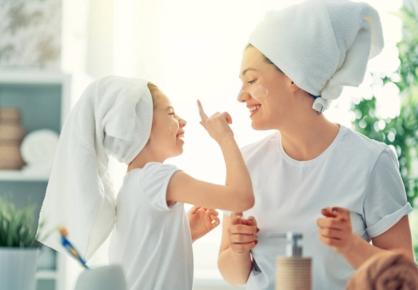 Happy family! Mother and daughter child girl are caring for skin in the bathroom. - Foto, immagini
