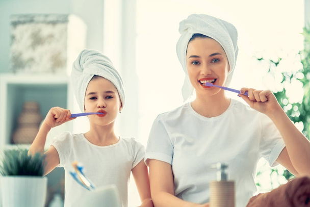 Happy family! Mother and daughter child girl are brushing teeth toothbrushes in the bathroom. - Foto, Bild