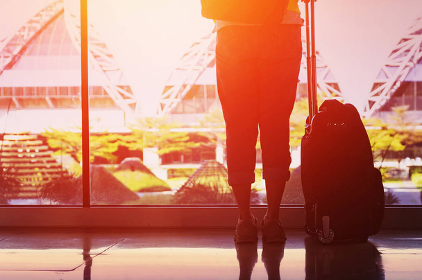 Genç kadın havaalanında pencere yanında duruyor. O ayakta ve Bagaj Taşıma. Seyahat kavramı . - Fotoğraf, Görsel