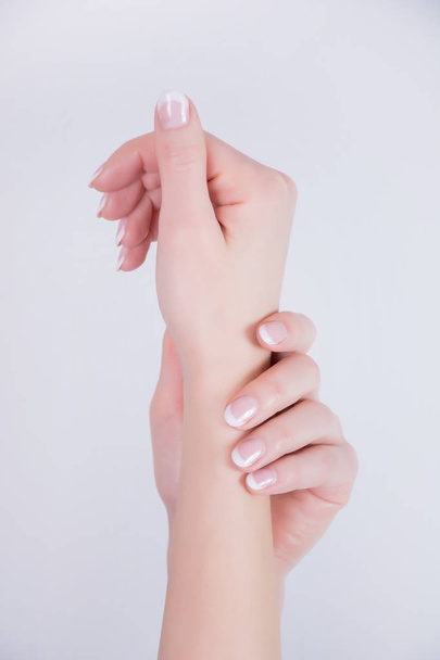 Молодая женщина руки с французскими ногтями маникюр стиле изолированы на белом фоне в студии. Красота и лак для ногтей. Крупный план, избирательный фокус
 - Фото, изображение