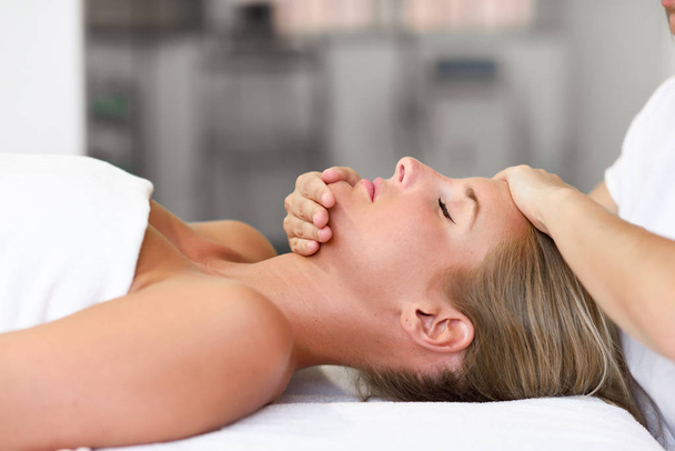 jonge vrouw het ontvangen van een hoofd massage in een spa centrum. - Foto, afbeelding