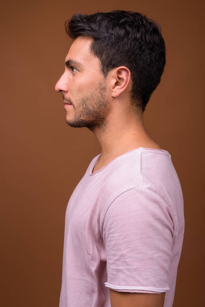 Young handsome Hispanic man against brown background - Foto, Imagem
