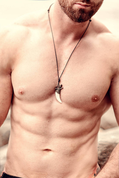 fashion photo of sexy torso of handsome sportsman with pendant in the form of a claw on his chest - Foto, Imagem