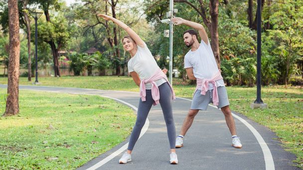 Una joven pareja se calienta y hace ejercicio en el parque
 - Foto, Imagen