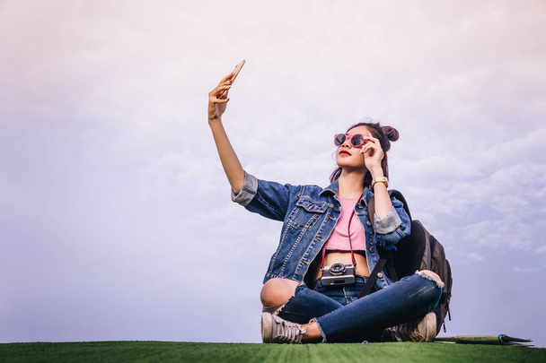 Woman sitting on green grass smiling on the day and photograph selfie  smartphone - Zdjęcie, obraz