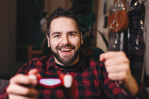Portret młodego mężczyzny, grania w gry wideo w jego salonie, szczęśliwy, ponieważ on wygrywa - Zdjęcie, obraz
