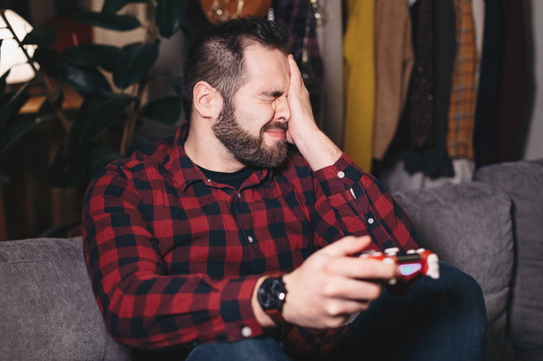 Portrait of a young man losing at playing video games, disappointed and angry because of the outcome. - Foto, immagini