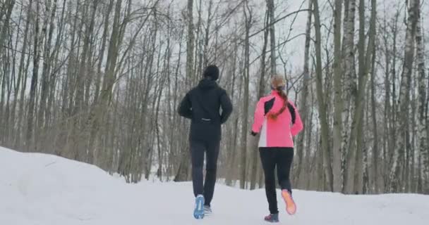 Kaunis nainen ja mies juoksevat metsässä talvella oikea ravitsemus ja terveellinen elämäntapa. Hidastus
. - Materiaali, video