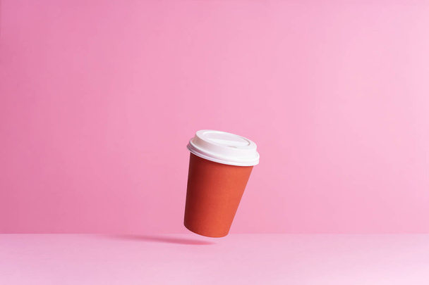 Disposable coffee cup in the air over pink background - Photo, Image