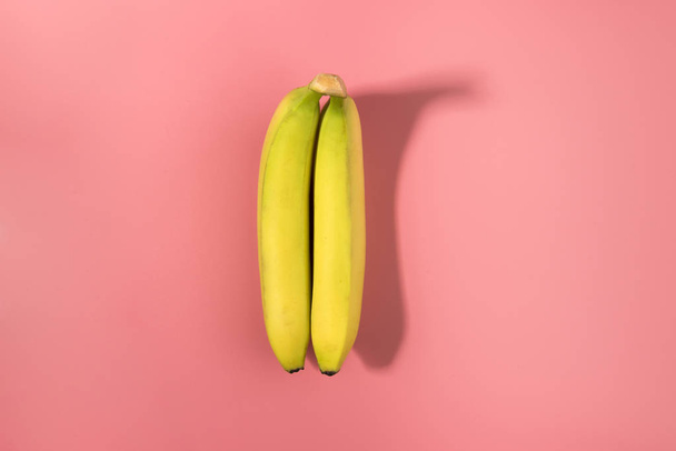 Two bananas isolated on a pink background with contrast shadow - Fotoğraf, Görsel