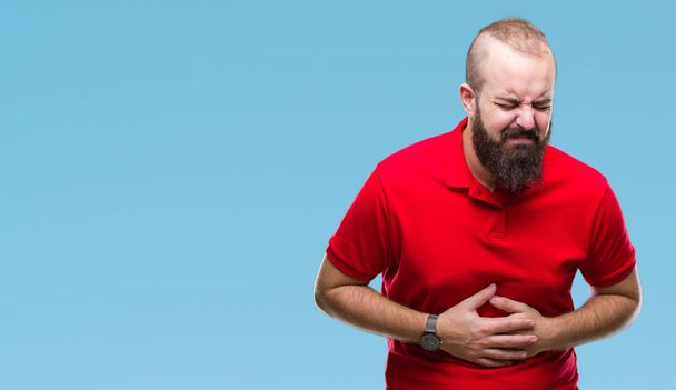 Young caucasian hipster man wearing red shirt over isolated background with hand on stomach because nausea, painful disease feeling unwell. Ache concept. - Fotó, kép