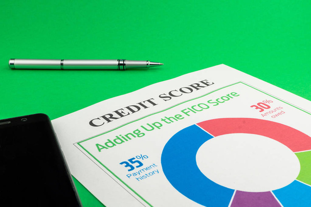 Credit score report with pen and smartphone on a green table. - Photo, Image