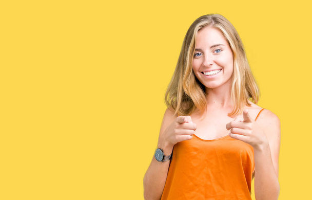schöne junge Frau, die orangefarbenes Hemd über isoliertem Hintergrund trägt und mit dem Finger in die Kamera zeigt, mit fröhlichem und lustigem Gesicht. gute Energie und Stimmung. - Foto, Bild