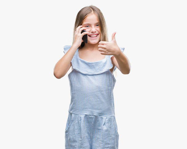Krásná mladá dívka mluví po telefonu izolované pozadí šťastný s velkým úsměvem dělá znamení ok, palec nahoru s prsty, vynikající značka - Fotografie, Obrázek