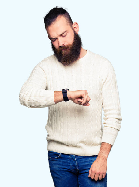 Joven hombre hipster con suéter de invierno Comprobación de la hora en el reloj de pulsera, relajado y seguro
 - Foto, imagen