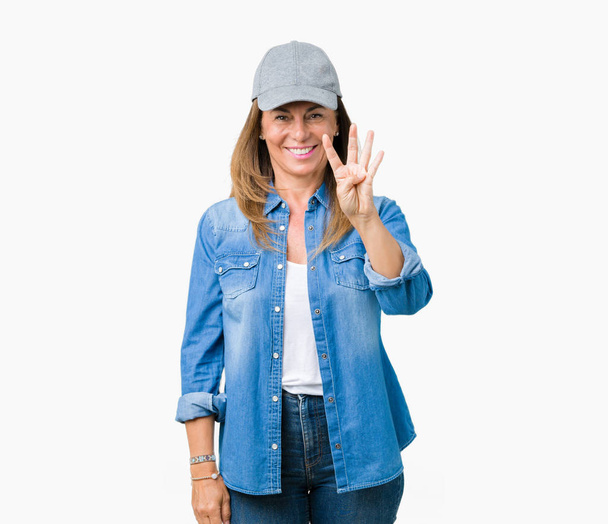 schöne Frau mittleren Alters trägt Sportkappe über isoliertem Hintergrund zeigt und zeigt mit Fingern Nummer vier, während sie selbstbewusst und glücklich lächelt. - Foto, Bild