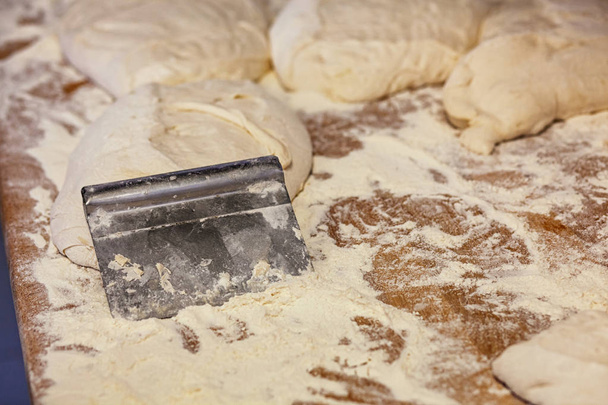 Cortar la masa para pan en la mesa de madera con pan crudo y harina
. - Foto, imagen