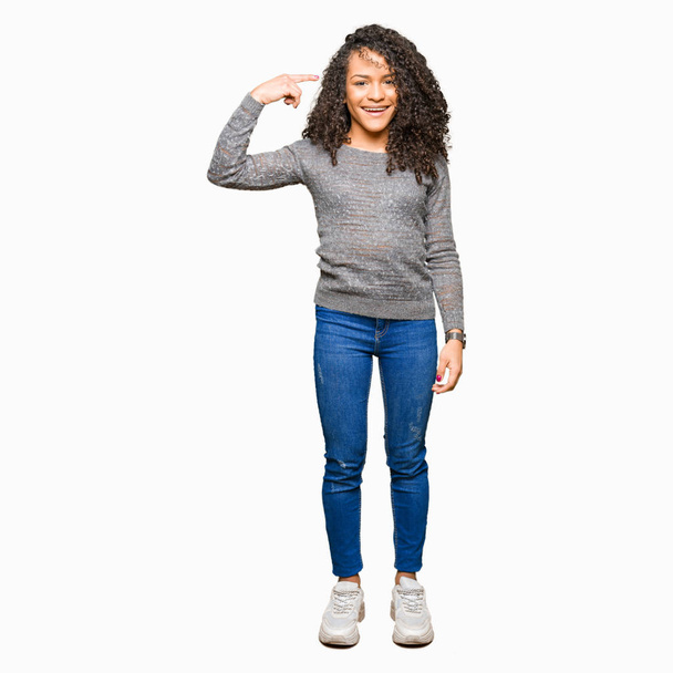 Young beautiful woman with curly hair wearing grey sweater Smiling pointing to head with one finger, great idea or thought, good memory - Foto, Imagen